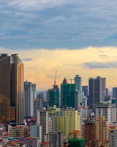 A panoramic view of Phnom Penh City's skyline, showcasing modern skyscrapers against a vibrant sunset backdrop.