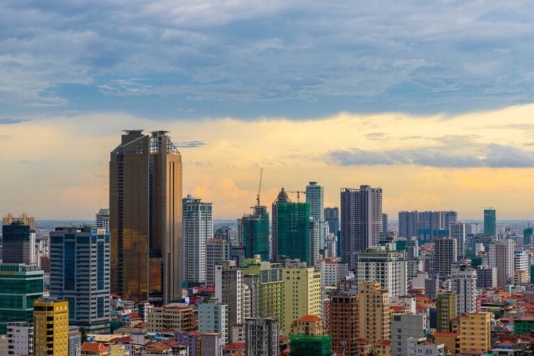 A panoramic view of Phnom Penh City's skyline, showcasing modern skyscrapers against a vibrant sunset backdrop.