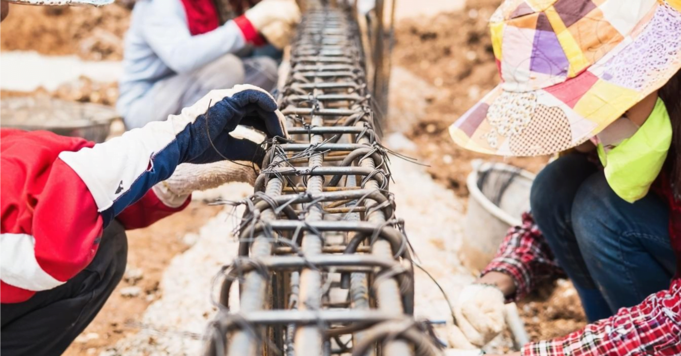 Construction workers diligently installing a steel fence at a job site, showcasing teamwork and Foreign Investment in Cambodian Construction.