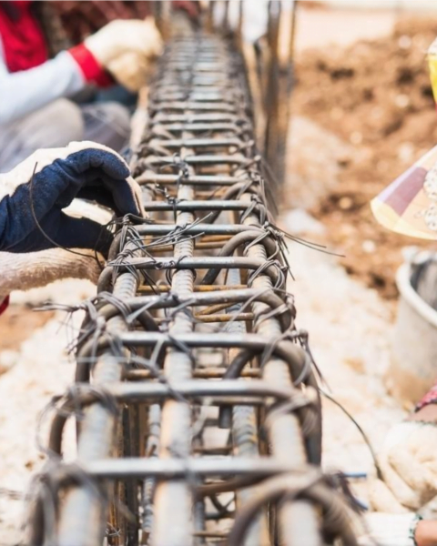 Construction workers diligently installing a steel fence at a job site, showcasing teamwork and Foreign Investment in Cambodian Construction.