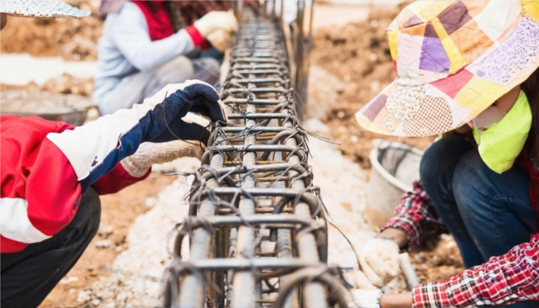 Construction workers diligently installing a steel fence at a job site, showcasing teamwork and Foreign Investment in Cambodian Construction.