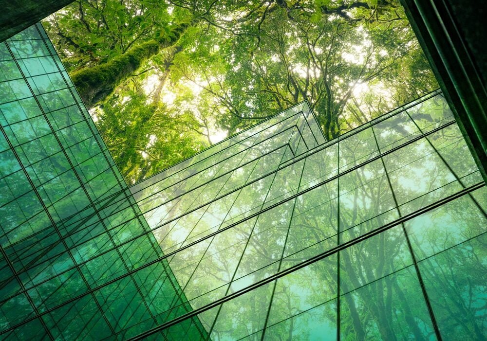 A glimpse of a glass building's interior in Cambodia, highlighting sustainable practices with greenery and trees throughout.