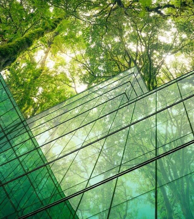 A glimpse of a glass building's interior in Cambodia, highlighting sustainable practices with greenery and trees throughout.