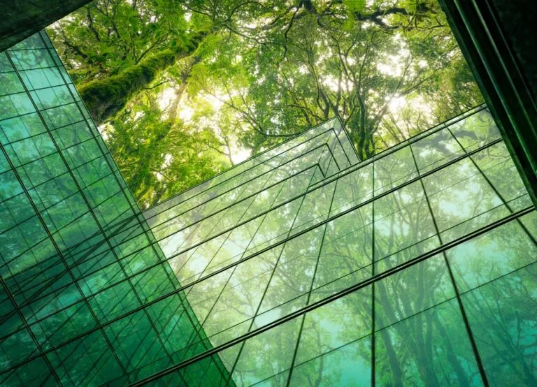 A glimpse of a glass building's interior in Cambodia, highlighting sustainable practices with greenery and trees throughout.