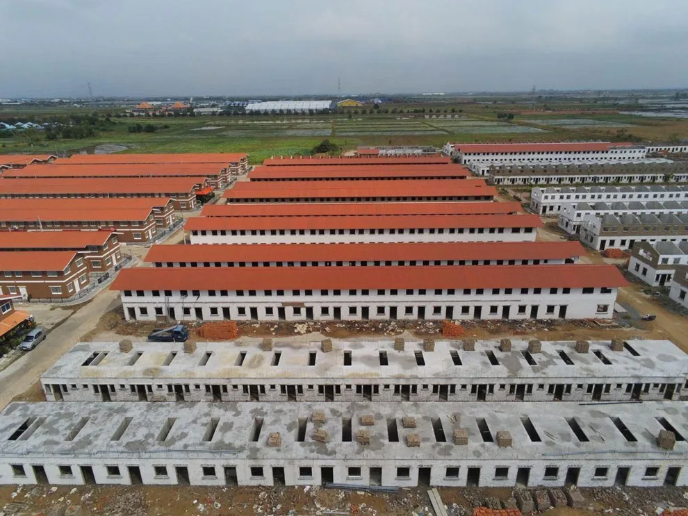 Aerial view of Affordable Housing in Cambodia's construction site with rows of unfinished buildings with red roofs.