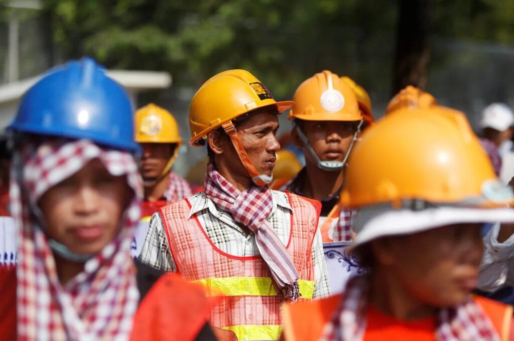 A group of Cambodian construction workers in construction hats walking together, showcasing the local Labor Market in Cambodian Construction.