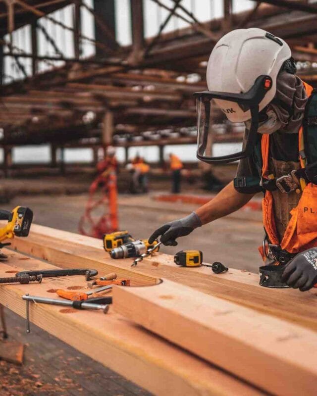 A man skillfully working on a wooden plank in a Cambodian factory, showcasing the need for Labor Market in Cambodian Construction.