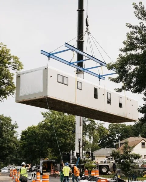 A modular home section being lifted by a crane with workers overseeing the process, symbolising Modular Construction in Cambodia.