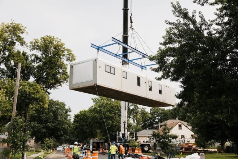 A modular home section being lifted by a crane with workers overseeing the process, symbolising Modular Construction in Cambodia.