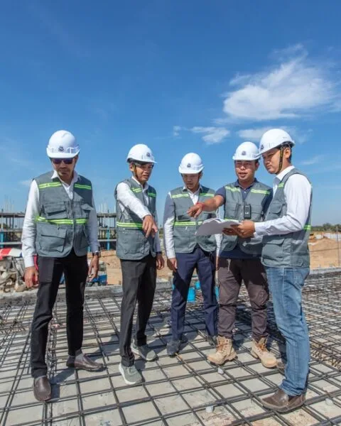 Group of construction workers with helmets on a building site in Cambodia, showing the needs of Cambodia Construction Safety Standards.
