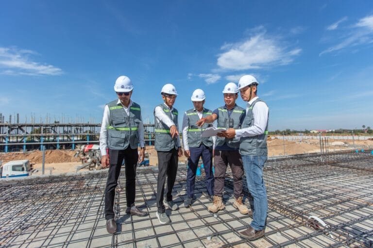 Group of construction workers with helmets on a building site in Cambodia, showing the needs of Cambodia Construction Safety Standards.