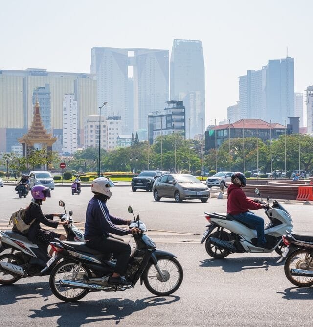 Phnom,Penh,,Cambodia,-,February,13,,2024:,Road,Traffic,In Motorcyclists on Phnom Penh city road with cars and modern skyscrapers in the background, showing the needs of Affordable Housing in Cambodia.