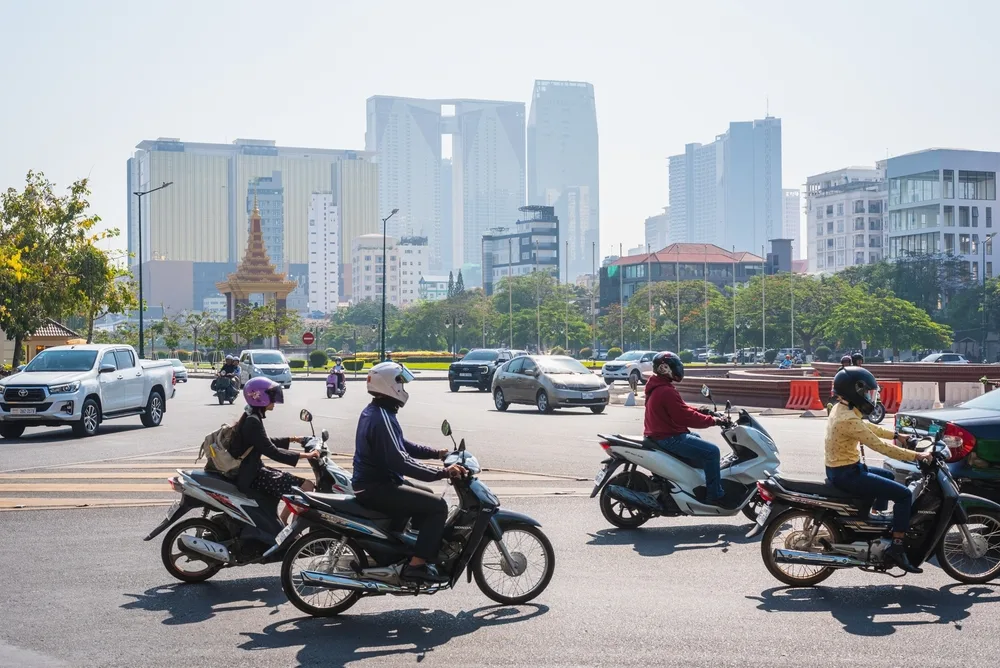 Phnom,Penh,,Cambodia,-,February,13,,2024:,Road,Traffic,In Motorcyclists on Phnom Penh city road with cars and modern skyscrapers in the background, showing the needs of Affordable Housing in Cambodia.