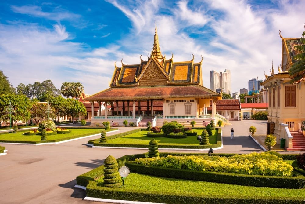 Real Estate Development in Cambodia: Traditional Cambodian palace with ornate golden roofs, landscaped gardens, and modern city backdrop.