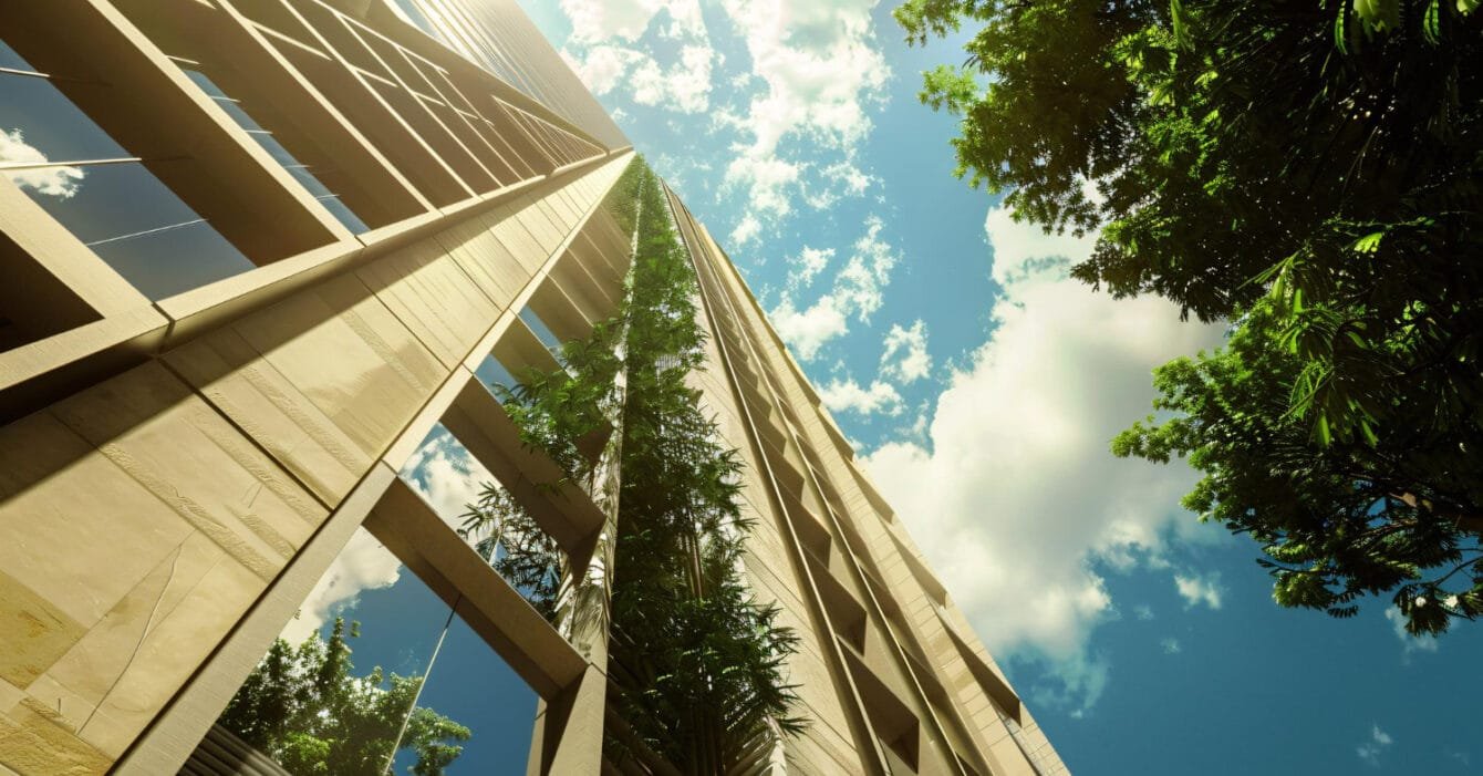 Low angle view of a tall building with green trees against a sunny sky, showing Cambodia Green Building Projects.