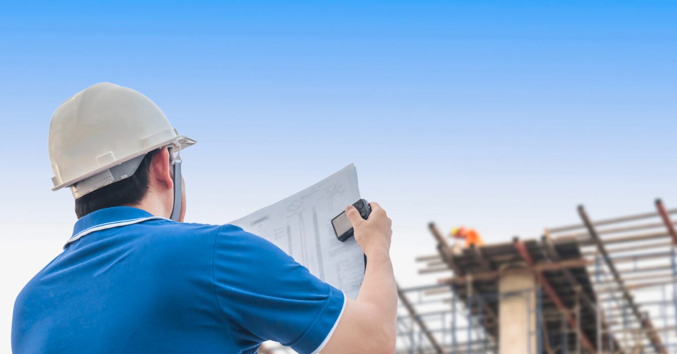 Engineer in hard hat reviewing plans at construction site, looking at Cambodia Construction Market Outlook 2025.