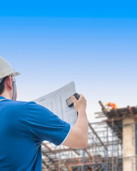 Engineer in hard hat reviewing plans at construction site, looking at Cambodia Construction Market Outlook 2025.