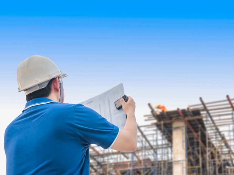 Engineer in hard hat reviewing plans at construction site, looking at Cambodia Construction Market Outlook 2025.
