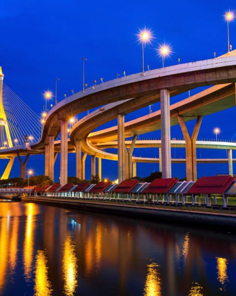 Illuminated suspension bridge and reflecting water at dusk to symbolise Cambodia Construction Market Growth Drivers.