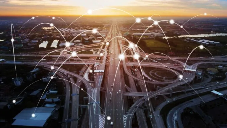 Aerial view of a bustling highway at sunset, overlaid with light connections depicting a networked transportation system to symbolise Cambodia Infrastructure Connectivity.