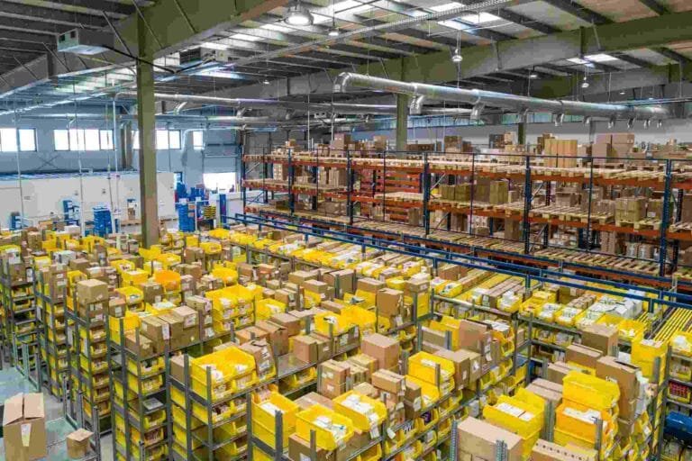 Cambodia Logistics Infrastructure Development: A spacious warehouse filled with yellow bins and stacked boxes on shelves, highlighting an organized distribution environment.