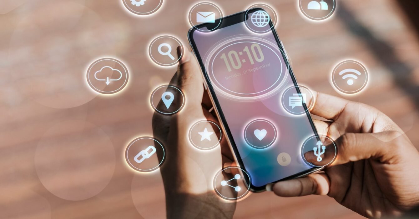 Cambodia Digital Service Growth: A person holds a smartphone displaying the time and date, surrounded by floating icons representing various apps and features.