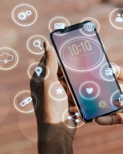 Cambodia Digital Service Growth: A person holds a smartphone displaying the time and date, surrounded by floating icons representing various apps and features.