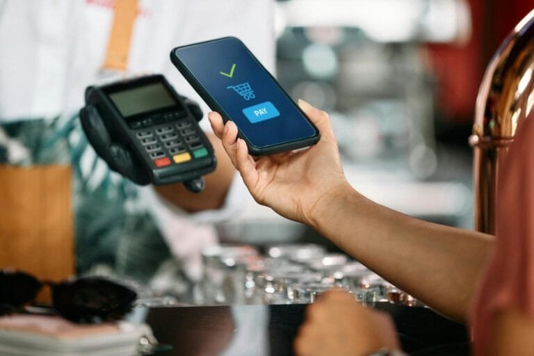 Cambodia Mobile Payments Surge: A customer using a smartphone for contactless payment at a checkout counter, with a card reader in the foreground.