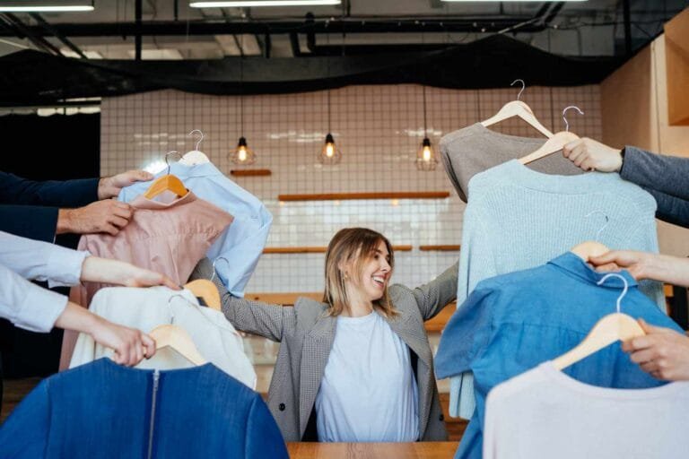 Cambodia Garment Export Diversifies: A woman surrounded by multiple hands holding various stylish clothing items in a modern retail setting.