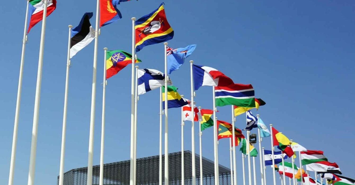 saj-shafique-mIalf1tw6-w-unsplash Cambodia Border Trade Restart: A row of international flags waving in the wind against a clear blue sky, symbolizing global unity and diversity.