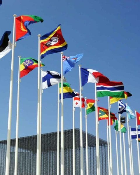 Cambodia Border Trade Restart: A row of international flags waving in the wind against a clear blue sky, symbolizing global unity and diversity.
