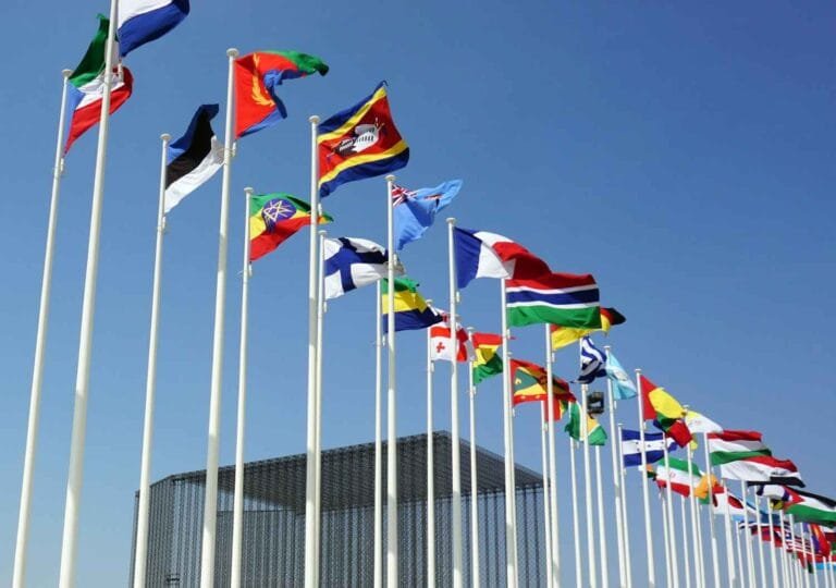 Cambodia Border Trade Restart: A row of international flags waving in the wind against a clear blue sky, symbolizing global unity and diversity.