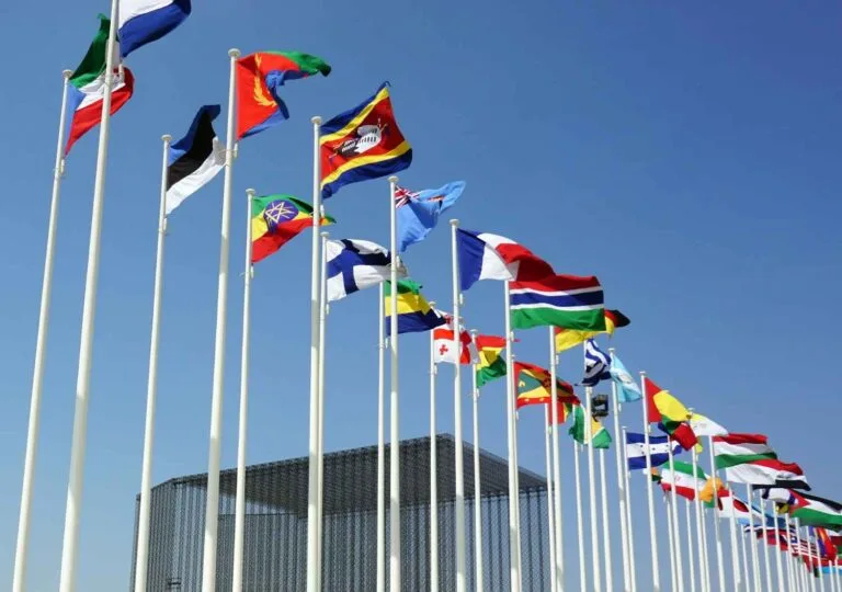 Cambodia Border Trade Restart: A row of international flags waving in the wind against a clear blue sky, symbolizing global unity and diversity.