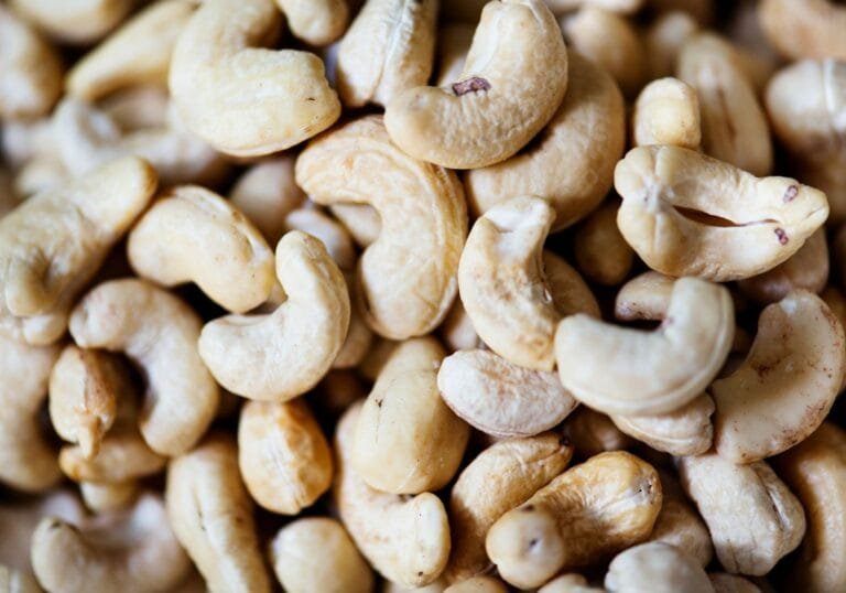 Cambodia cashew processing: A close-up image of a pile of raw cashew nuts, showcasing their creamy texture and curved shapes.